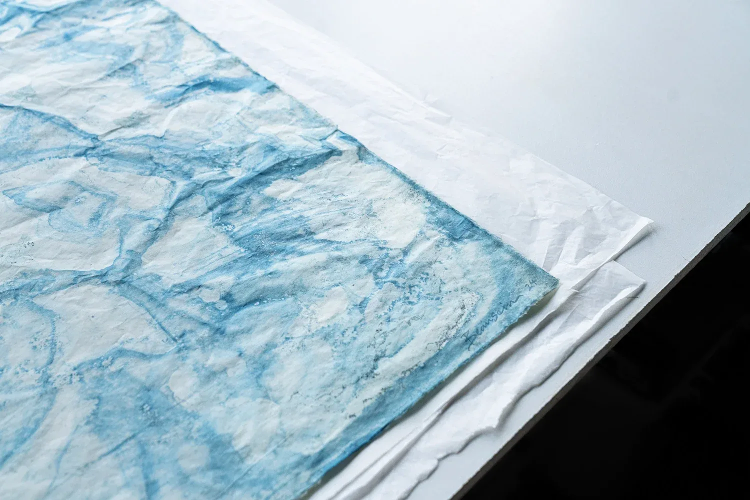 An angled view of a pale blue artwork and its layered edge.