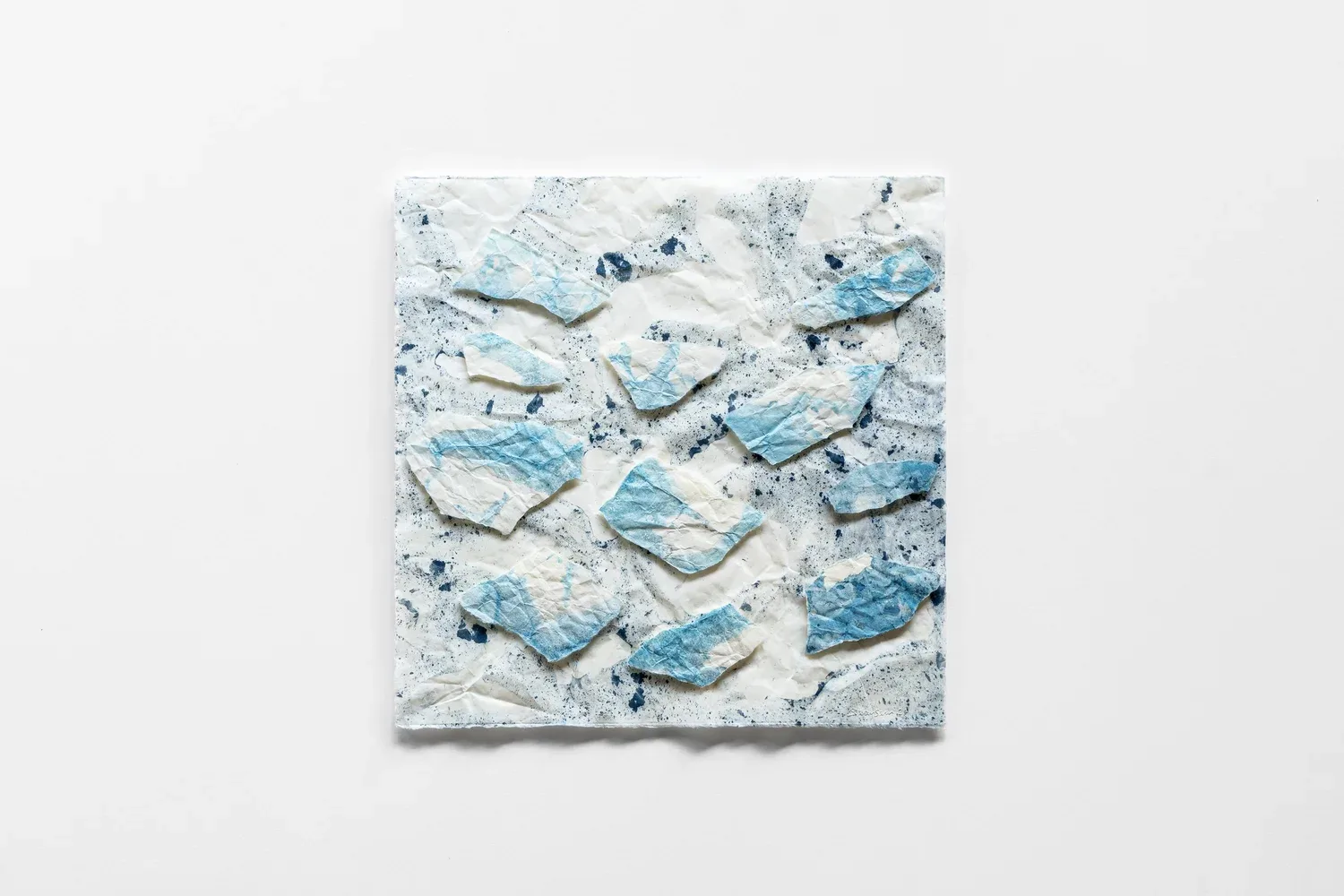 Raised and folded surfaces within a pale artwork.