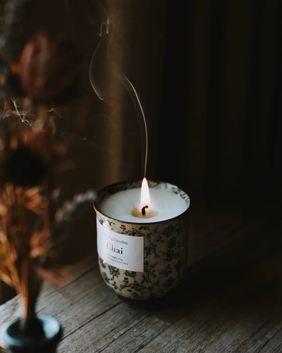 A pale candle surface and flame in warm light.