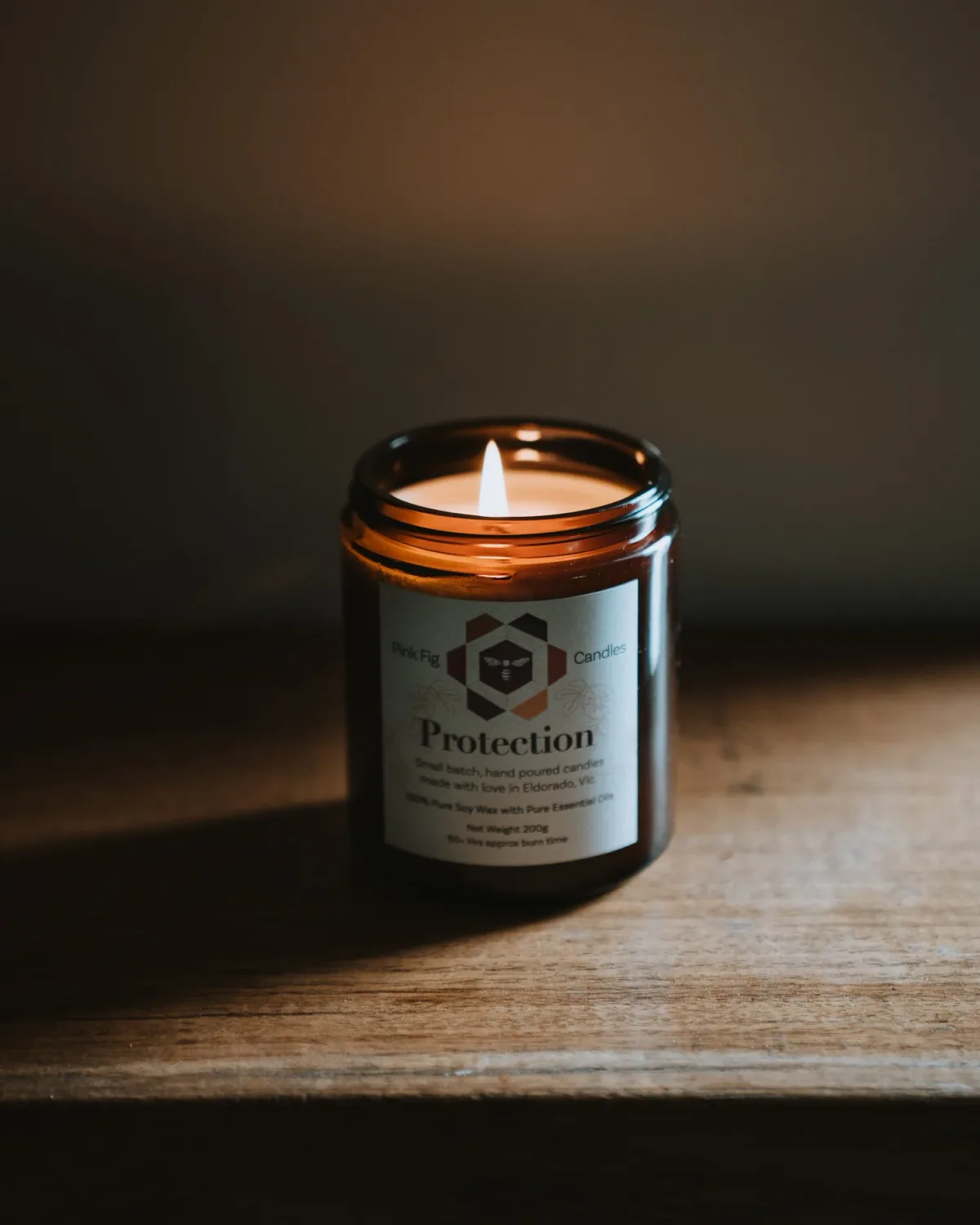 A lit Pink Fig candle in its labelled glass vessel.