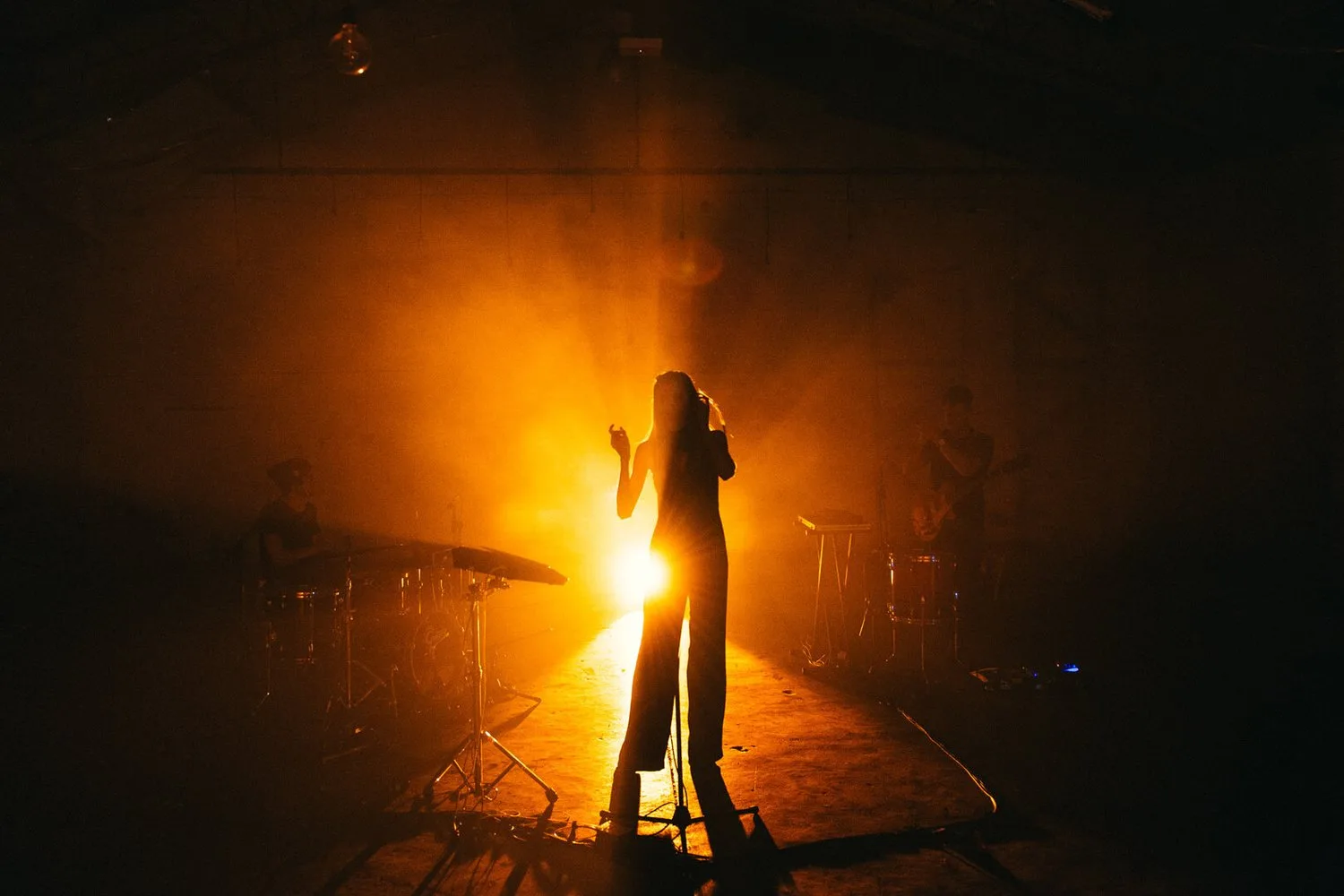 A performer held in a bright pool of warm stage light.