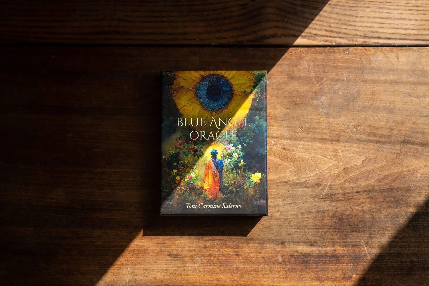 A Blue Angel Oracle book in a band of sunlight on timber.